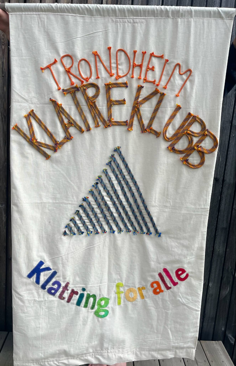 Klubbfanen vår inkluderer logo og bokstaver med klatretau, og symboliserer det mangfoldet vi ønsker å inkludere.